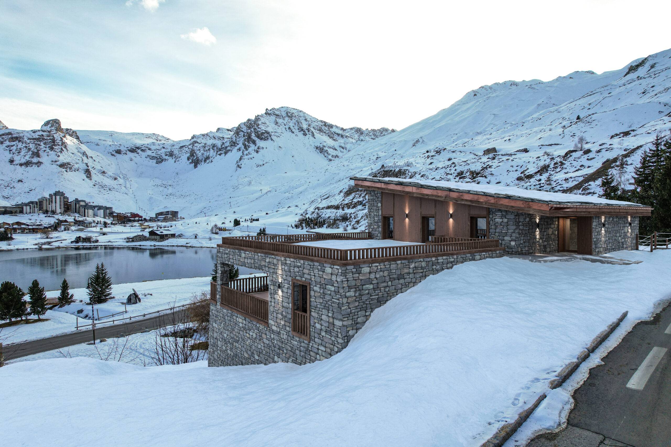 Rendu 3D Pierzo d'un chalet en pierre et bois à Tignes surplombant le lac gelé, illustrant une insertion paysagère chalet réussie en hiver.